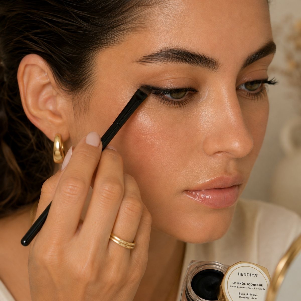 Applying Le Khôl Iconique by Hendiya with the liner brush to the eyes